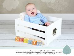 a baby is sitting in a wooden crate