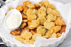 a white plate topped with tater tots and a small bowl of ranch dressing