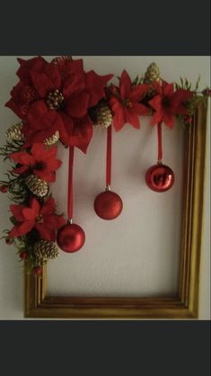 christmas decorations hanging on the wall in front of a frame with pine cones and poinsettis