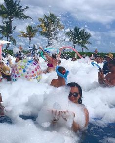 many people are playing in foam at the pool and having fun with eachother