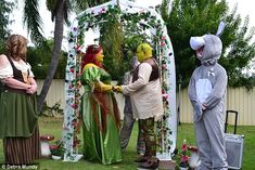 some people are dressed up in costumes and standing around an outdoor area with flowers on the grass