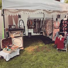 an outdoor tent with clothes on display in the grass next to other clothing and accessories