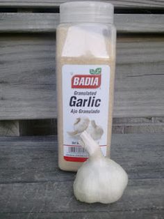 garlic is sitting next to a bottle of garlic oil on a wooden bench outside the building