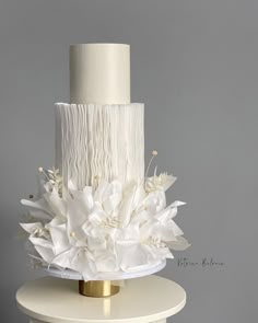 a three tiered cake with white flowers on top