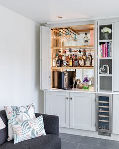 a living room filled with furniture and lots of bottles on top of the cabinet doors