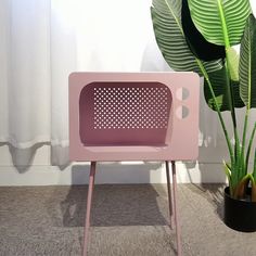 a pink chair sitting next to a potted plant