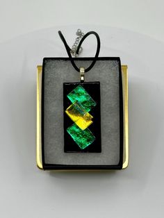 This stunning dichroic glass necklace is handmade by yours truly here in Eau Claire, Wisconsin. This beautiful one-of-a-kind piece measures 2" in height, and 1" in width. Each piece is topped with a sterling silver plated bail and comes with a 20" black leather cord upon purchase. Unique Iridescent Glass Necklaces, Iridescent Glass Necklaces As Gifts, Multicolor Recycled Glass Jewelry As A Gift, Multicolor Recycled Glass Jewelry For Gifts, Black Glass Jewelry Gift, Silver Murano Glass Jewelry Gift, Modern Green Necklace As A Gift, Modern Green Necklace For Gift, Modern Green Necklace As Gift