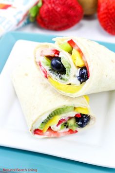 two wraps filled with fruit are sitting on a plate next to strawberries and bananas