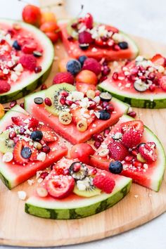 slices of watermelon and berries arranged on a wooden platter with other fruits