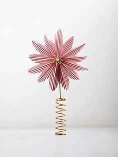 a pink paper flower with gold spirals in it's center on a white surface