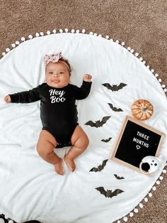 a baby is laying on a white blanket next to a blackboard with the words hey booy