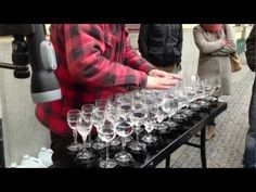 several people are standing around with many wine glasses on a table in front of them