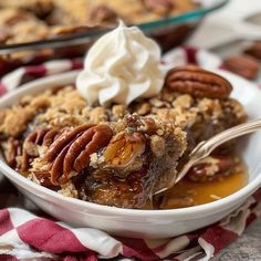 a close up of a bowl of food with pecans and whipped cream on top