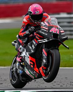 a man riding on the back of a motorcycle down a race track with his hand in the air