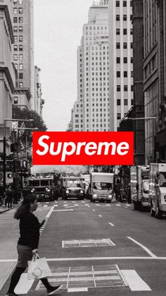 a black and white photo of a person crossing the street with a red supreme sign in the background