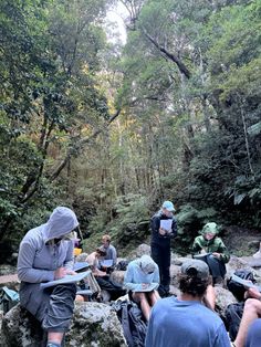 a group of people sitting on rocks in the woods