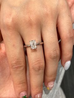 a close up of a person's hand with a diamond ring on their finger