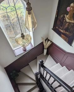 an aerial view of a stair case with paintings on the wall and a lamp hanging above it