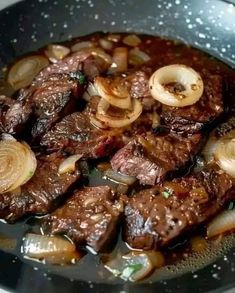 steak with onions and mushrooms cooking in a skillet