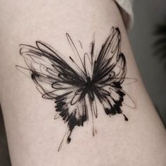 a black and white butterfly tattoo on the thigh