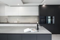 an open book is sitting on the counter in this modern kitchen with black and white cabinets