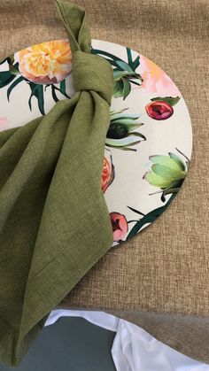 a plate with a green napkin on top of it next to a flowered placemat