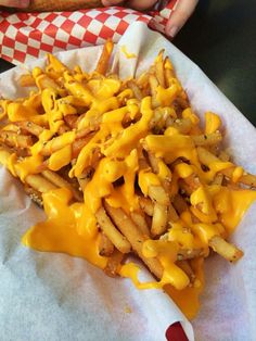 a basket filled with french fries covered in cheese