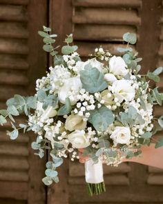 a bridal bouquet with white flowers and greenery