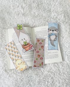 three bookmarks with pictures of animals and plants on them sitting on a white carpet