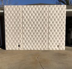 a large white wall sitting in the middle of a driveway next to a garage door