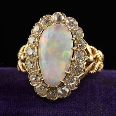 Beautiful Antique Victorian 18K Yellow Gold Natural Australian Opal Diamond Halo Ring. This gorgeous Victorian Australian opal diamond ring is crafted in 18k yellow gold. This ring features a gorgeous natural Australian opal in the center that has an incredible play of colors. The diamonds around the opal are chunky old mine cut stones. The ring is in great condition and sits low on the finger. Item #R2033 Metal: 18K Yellow Gold Weight: 5.1 Grams  Size: 6 1/2 Opal: Approximately 2.25 cts Diamonds: Approximately 2 cts Color: I Clarity: SI1 Measurements: Top of the ring measures 20.50 mm wide and band measures 2.42 mm wide. Measurements off the finger: 6.54 mm high Layaway: For your convenience, we will be happy to provide layaway payment options. Please contact us to work out a layaway plan Opal Ring Antique, Antique Yellow Gold Opal Ring, Luxury Victorian Opal Ring, Gold Victorian Luxury Opal Ring, Victorian Opal Yellow Gold Jewelry, Victorian Style Gold Opal Ring With Multi-stone, Opal Diamond Ring, Diamond Halo Ring, Halo Diamond Ring