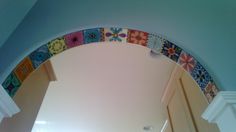 an arch in the ceiling has colorful tiles on it and is painted with white paint