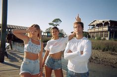 three people standing on a dock with their arms around each other and one person holding his head