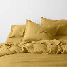 an unmade bed with yellow sheets and pillows