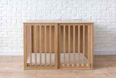 a wooden crib against a white brick wall in a room with hardwood flooring