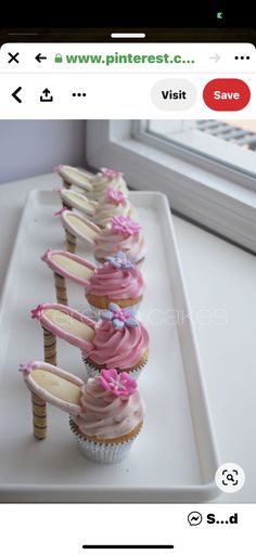 cupcakes with pink frosting and bows on them are lined up in a row