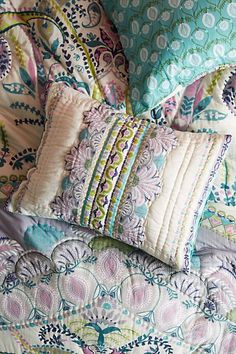 the pillows are stacked on top of each other in this bedding set with colorful patterns