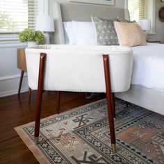 a white bed sitting on top of a wooden floor next to a lamp and rug