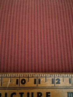 an old ruler is next to a red striped fabric