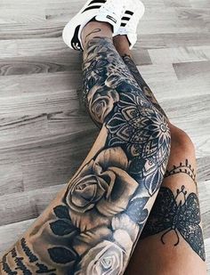 a woman's legs with tattoos and flowers on them, sitting on the floor