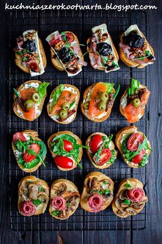 an assortment of sandwiches sitting on top of a black grill grate covered in toppings