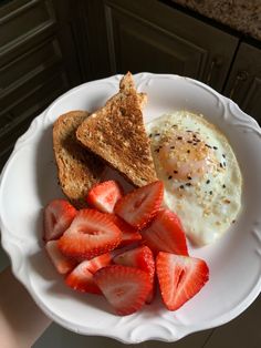 a white plate topped with toast, strawberries and an egg