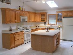 an empty kitchen with wooden cabinets and white counter tops is seen in this image from the front view