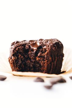 a chocolate muffin sitting on top of a paper plate with chocolate chips around it