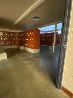 an empty room with red and white walls, concrete flooring and brick partitions