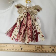 an angel ornament hanging on a white cloth with a measuring ruler next to it