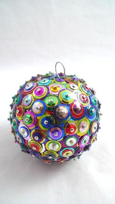 an ornament is decorated with multicolored circles and metal balls on a white background