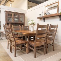 a dining room table with chairs and a vase on it's side, in front of a white wall