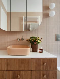 a bathroom with a sink, mirror and flowers in the vase on the counter top