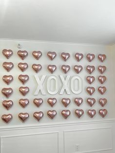 there are many heart shaped balloons hanging on the wall in front of the words xoxo